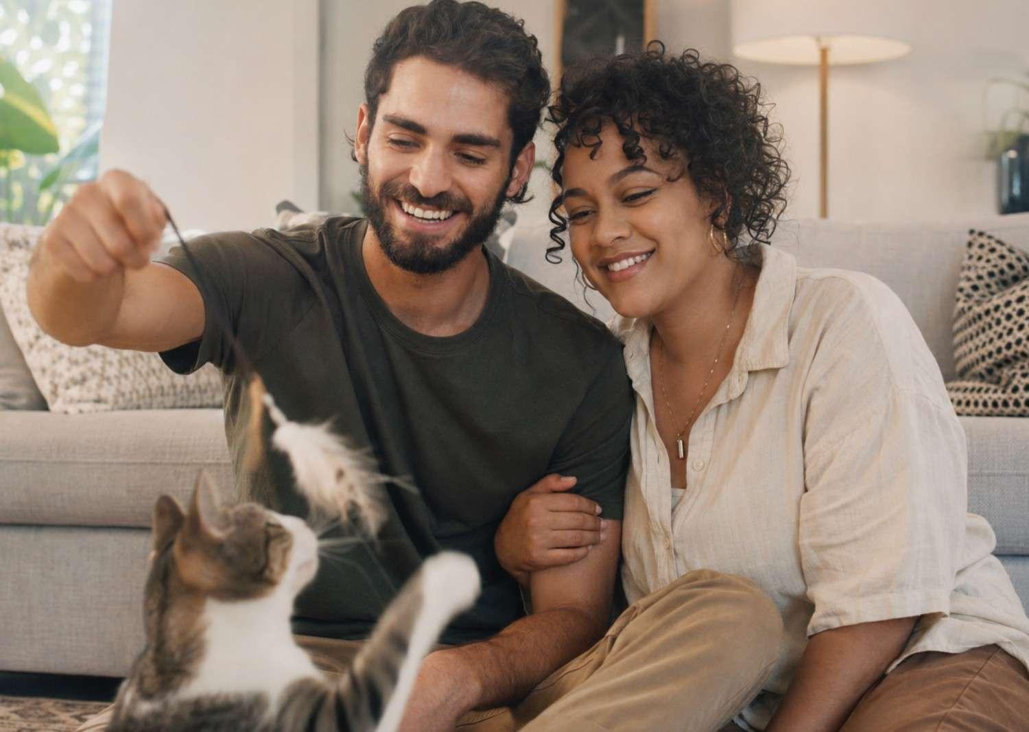 Couple playing with their cat at home for a possessive adjectives ESL lesson about relationships, pets, and using “our” to describe shared things.