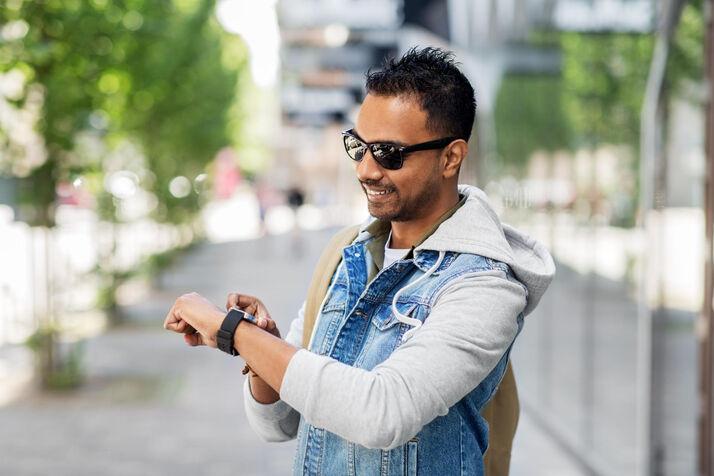 A man checking his wrist watch to tell the time, illustrating daily schedule and time expressions for ESL learners.